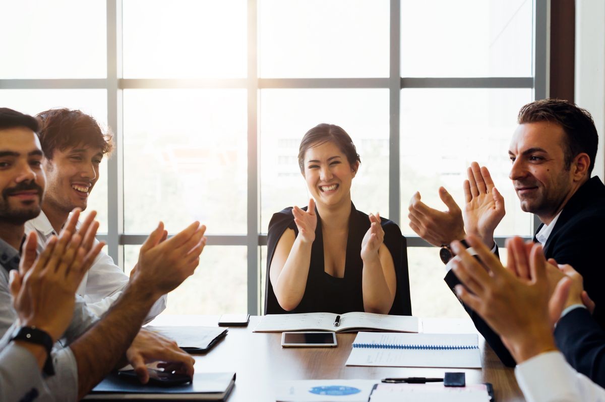 businesspersons clapping hands and applauding in business meeting conference. While female business executive sitting in front - woman power in corporate work